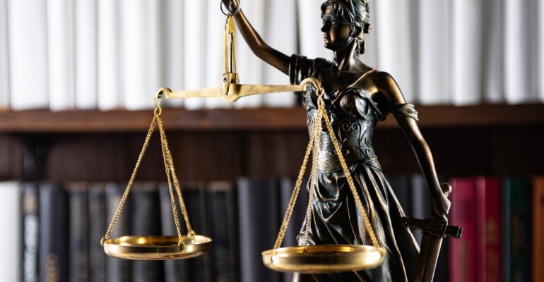 Scales of Justice, Lady Justice, law library concept, Law books in the background.