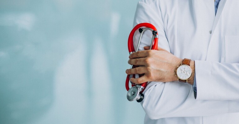 Young handsome physician in a medical robe with stethoscope