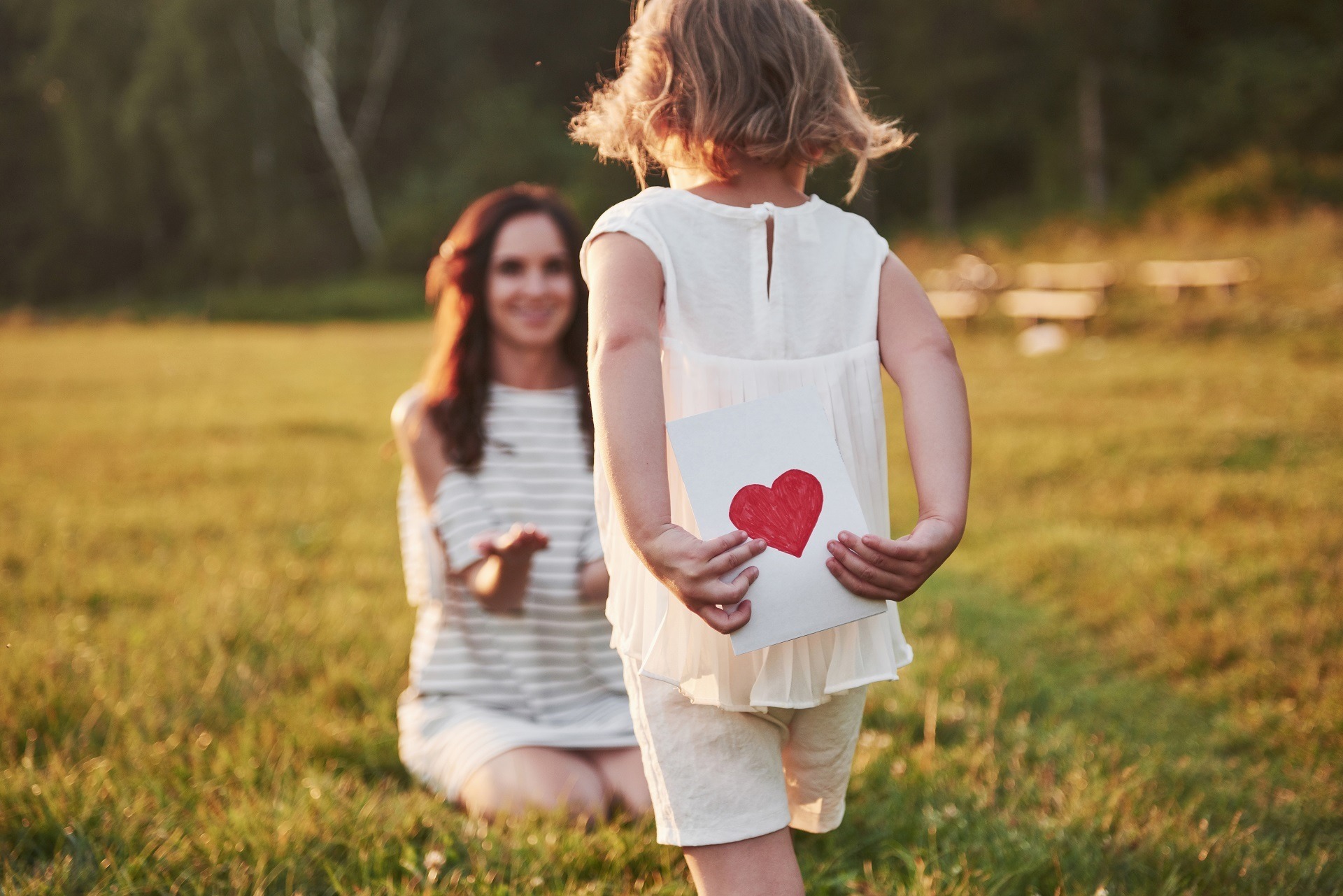 The child's daughter congratulates her mother and gives her a postcard. Mother and girl smile and hug.