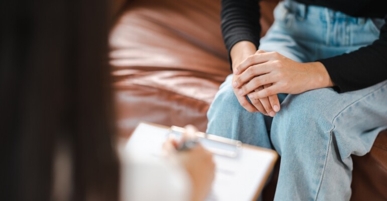 Psychologist making notes in medical history while understanding problems of a woman patient